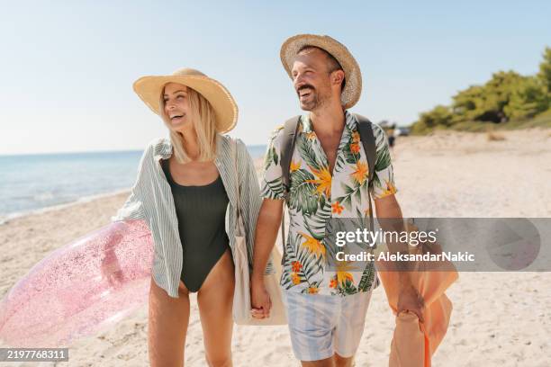 smiling couple arriving at the beach - badkläder bildbanksfoton och bilder