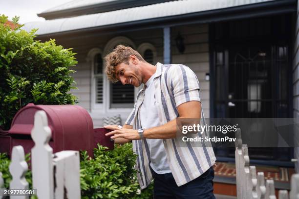joven revisando el correo fuera de una acogedora casa suburbana - buzón de cartas fotografías e imágenes de stock