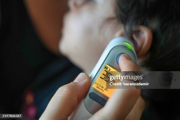 digital ear thermometer showing high fever in child - koorts stockfoto's en -beelden