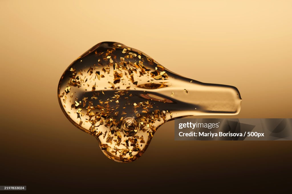 A delicious drop of 24k gold serum on a gold background