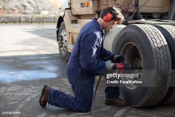 mechanic using air compressor drill to bolt new tire to a truck vehicle for tire repair in an auto garage - air screw compressor stock pictures, royalty-free photos & images