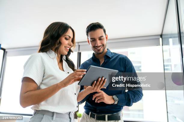 business people sharing ideas at the office while using a digital tablet - two people stock pictures, royalty-free photos & images