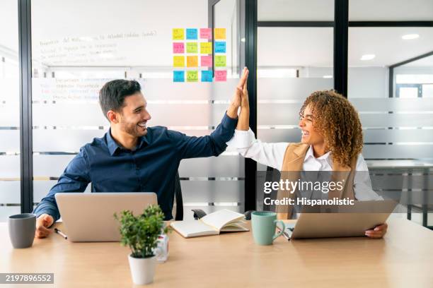 business team high-fiving while working together at the office - high five stockfoto's en -beelden