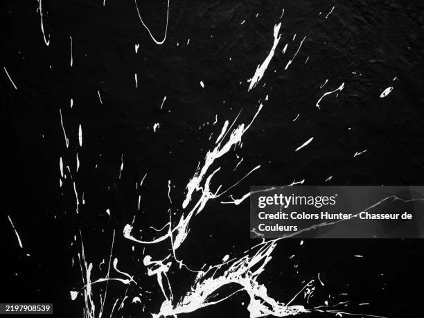 white paint splashes on a black concrete wall. rough texture. sunlight. black and white. paris, france. - splattered stock pictures, royalty-free photos & images