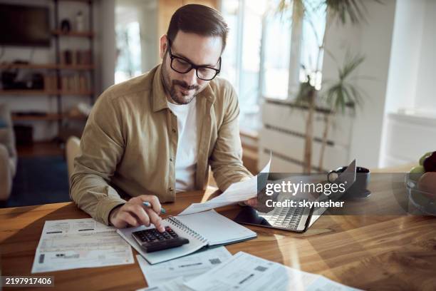 giovane che lavora sulle sue bollette finanziarie a casa. - tasse foto e immagini stock