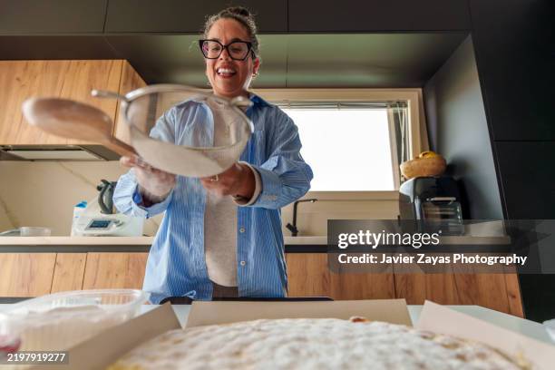 middle-aged woman baking cake in modern kitchen - sifting stock pictures, royalty-free photos & images