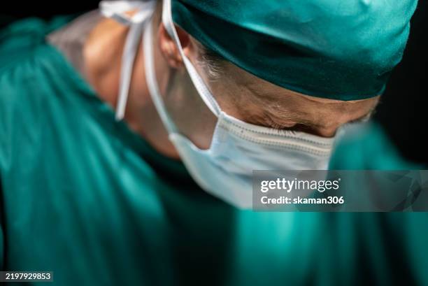 experienced surgeon operating on patient - successful treatment in hospital operating room - medizinerkleidung stock-fotos und bilder