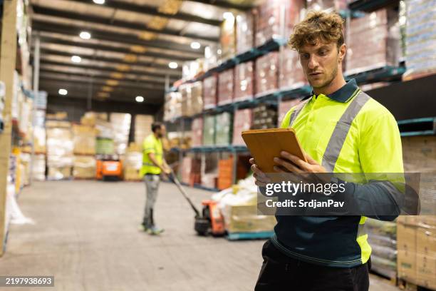 worker using tablet in a large warehouse with storage racks - inventory management stock pictures, royalty-free photos & images