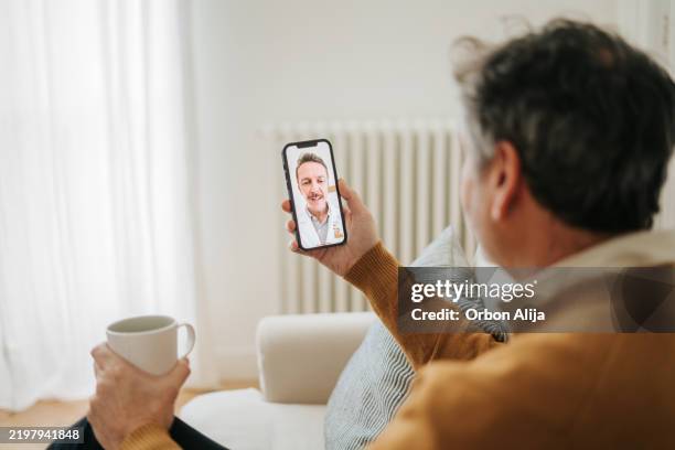 man having a doctor's appointment online using smart phone - doctor zoom stock pictures, royalty-free photos & images