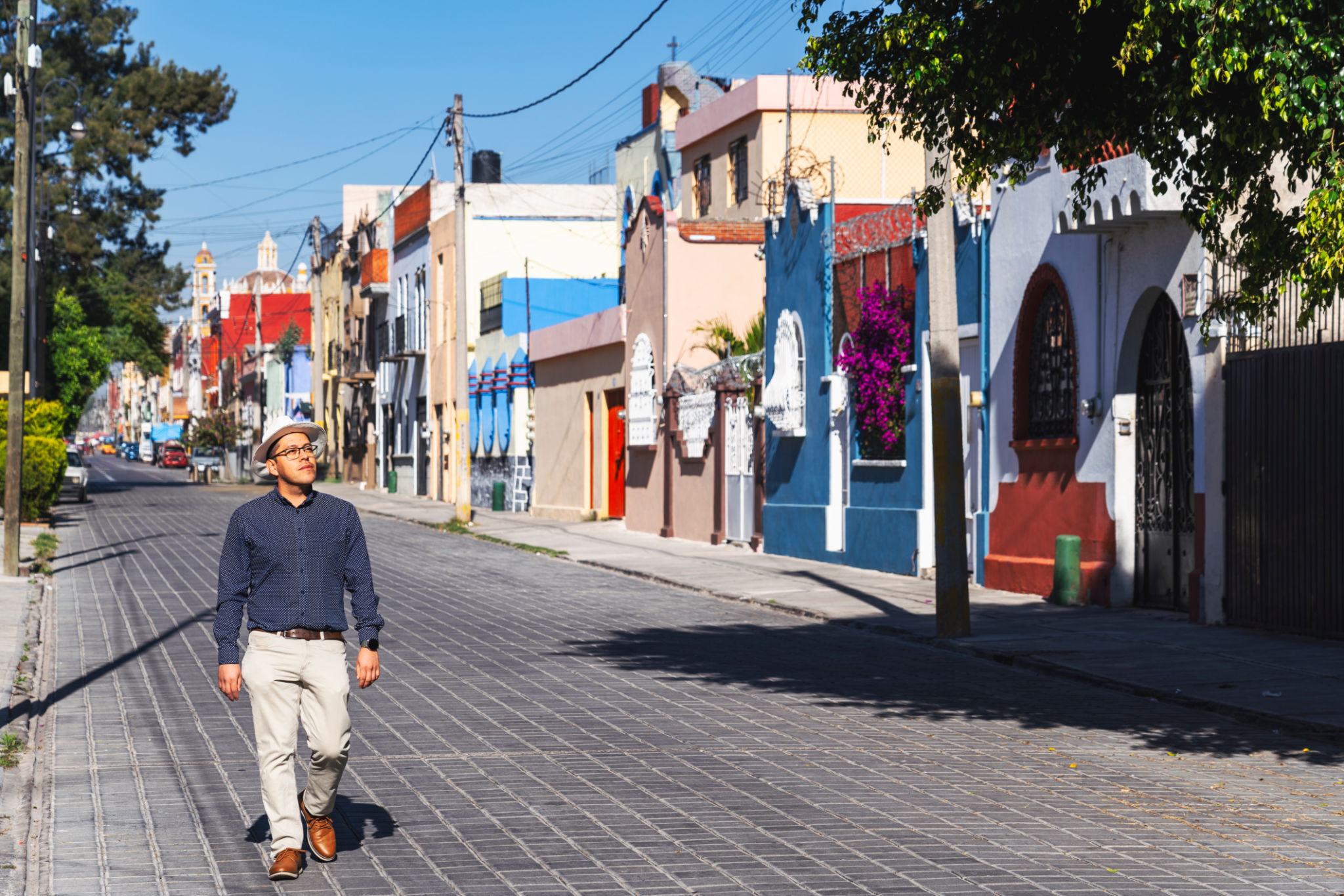 A man walking a street of Puebla lined with colorful houses A man walking a street of Puebla lined with colorful houses