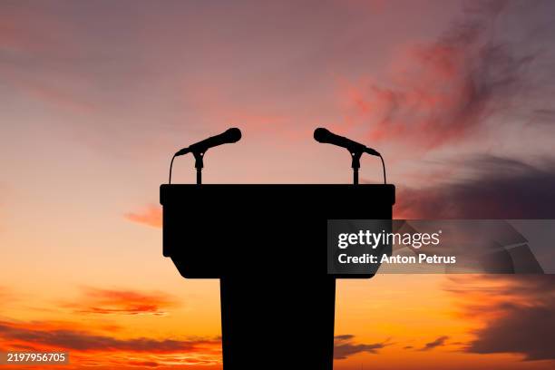 podium with microphone against sunset background - mikrofonständer stock-fotos und bilder