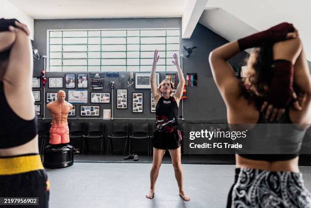 female fighters stretching before muay thai class at gym - martial arts stock pictures, royalty-free photos & images