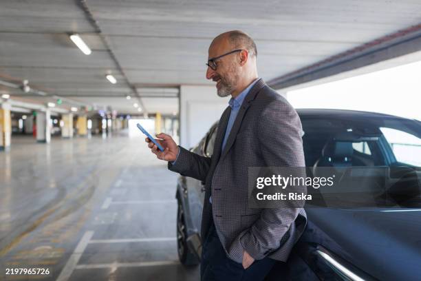 a businessman using a phone before leaving a garage - car payment stock pictures, royalty-free photos & images