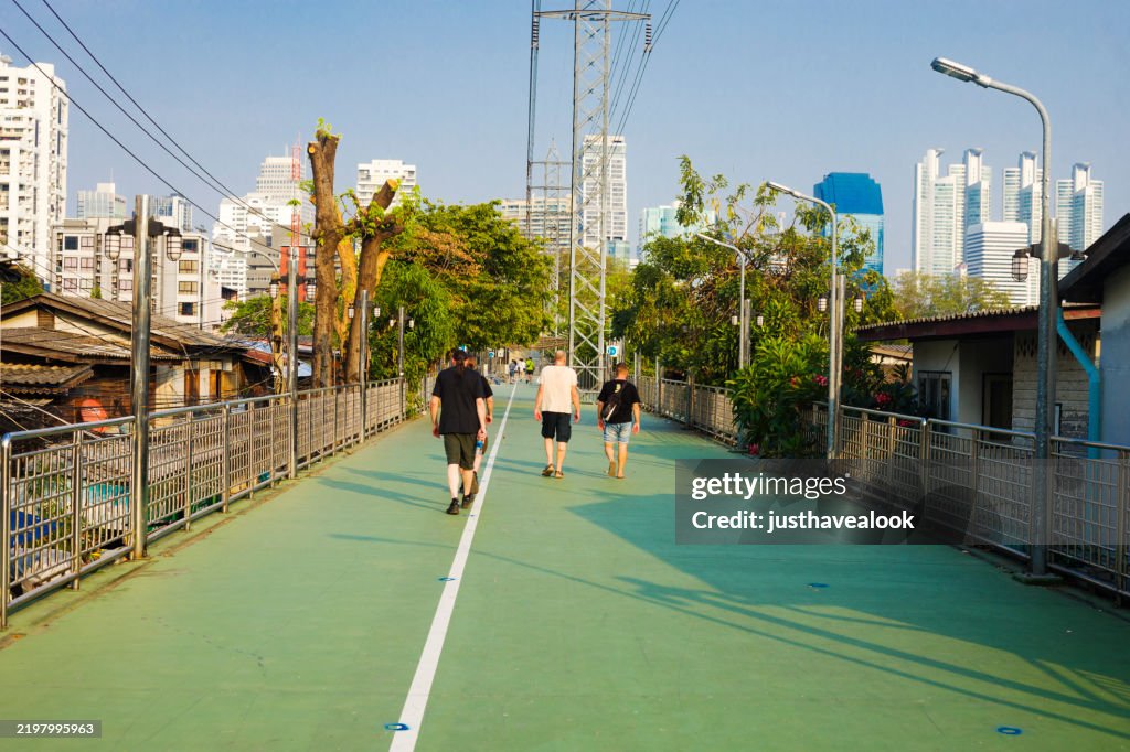 Rear view of walking white men on skywalkThe Green Bridge, Lumphini-Benchakitti Park
