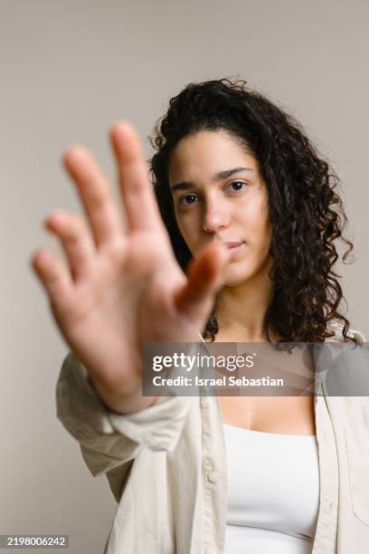 young latina woman making stop gesture with serious expression - geschlechtsdiskriminierung stock-fotos und bilder