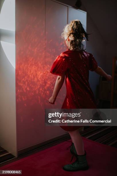 a child twirls around wearing a red sequin dress - sequin dress stock pictures, royalty-free photos & images