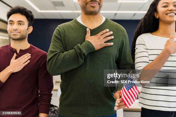 eine multiethnische gruppe von erwachsenen schwört der us-flagge die treue - amerikanischer treueschwur stock-fotos und bilder