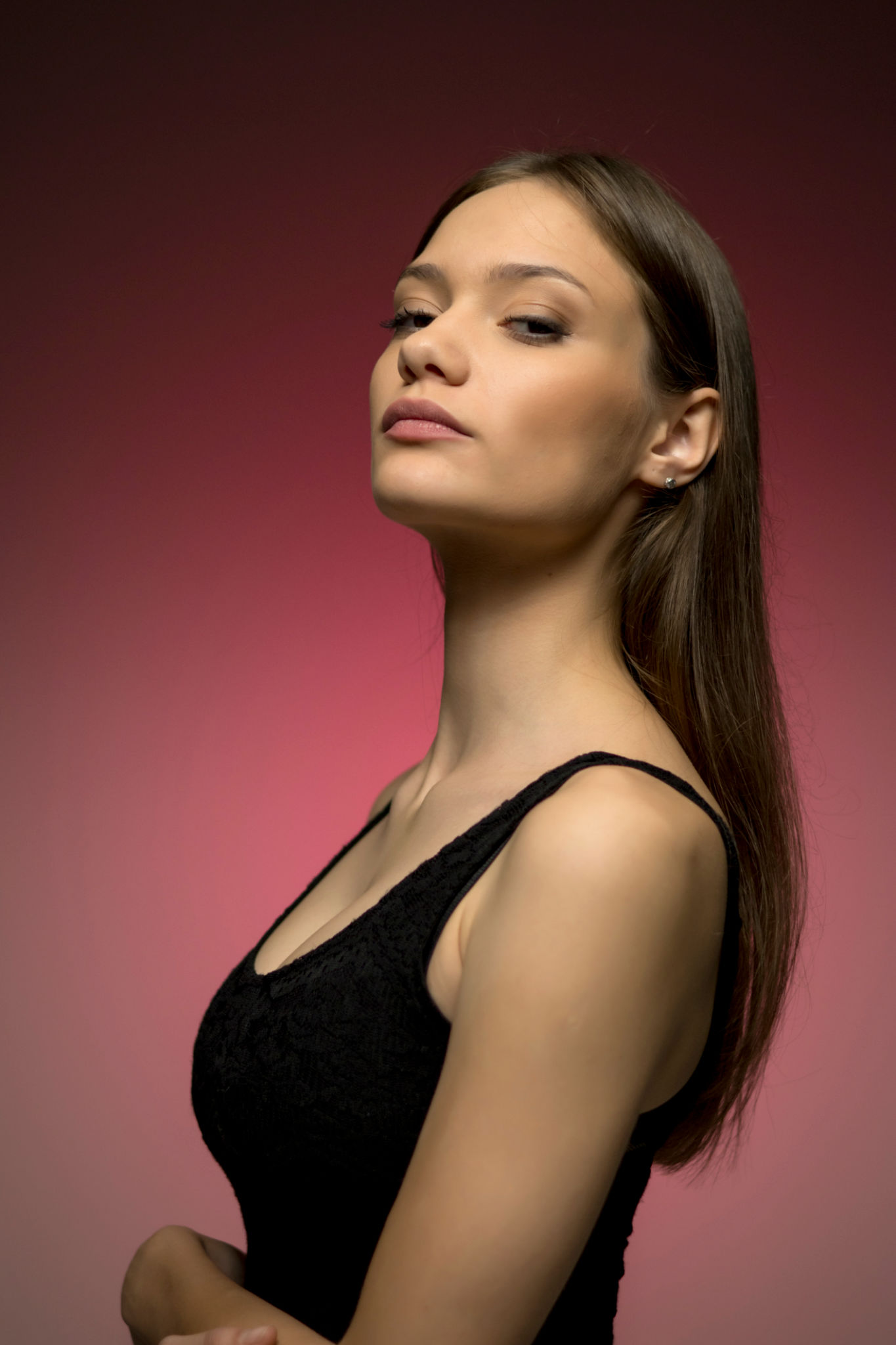 Dramatic upward angle portrait with pink gradient background. Model's confident pose and elegant profile create powerful fashion aesthetic Dramatic upward angle portrait with pink gradient background. Model's confident pose and elegant profile create powerful fashion aesthetic