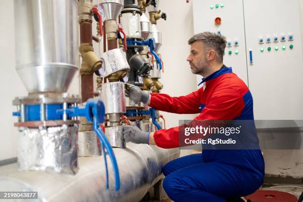 a worker is performing maintenance on the heating system - district heating stock pictures, royalty-free photos & images