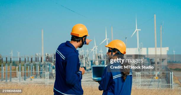 ingenieros discuten con una computadora portátil en una estación de generación de energía eólica, poniendo en primer plano la sinergia entre la tecnología y los recursos renovables. generación de energía verde y ecológica, energía eólica sosteni - suministro de energía fotografías e imágenes de stock