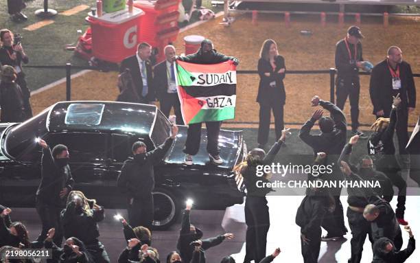 Protestor holds a Palestinian flag with the words "Gaza" and "Sudan" as US rapper Kendrick Lamar performs during Super Bowl LIX Chiefs vs Eagles...