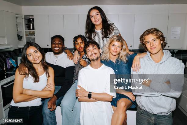 portrait of multiracial male and female friends posing in dorm room kitchen - groepsfoto stockfoto's en -beelden