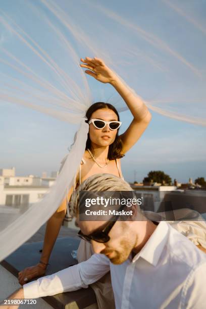 young woman and man sitting under veil on rooftop - wedding berlin stock pictures, royalty-free photos & images