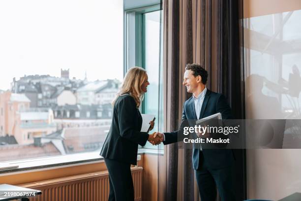 happy male and female business professionals doing handshake at office - handskakning bildbanksfoton och bilder