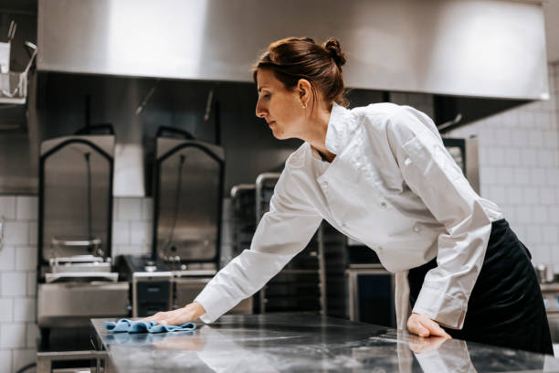 low angle view of female chef cleaning kitchen counter in restaurant - cleaning stock pictures, royalty-free photos & images