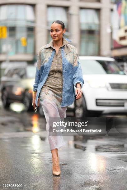 Sai De Silva wears silver earrings, dark plaid pattern collar shirt, light blue pattern/print oversized unbuttoned pattern/print long sleeve shirt,...