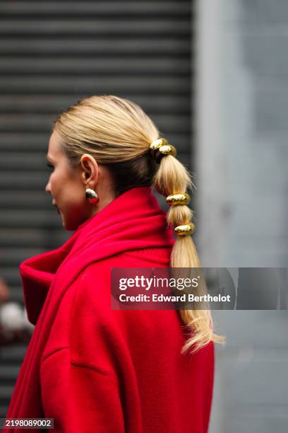 Guest wears a red scarf, red wool top, golden jewelry as attachments for the ponytail, earrings, outside Brandon Maxwell, during New York Fashion...