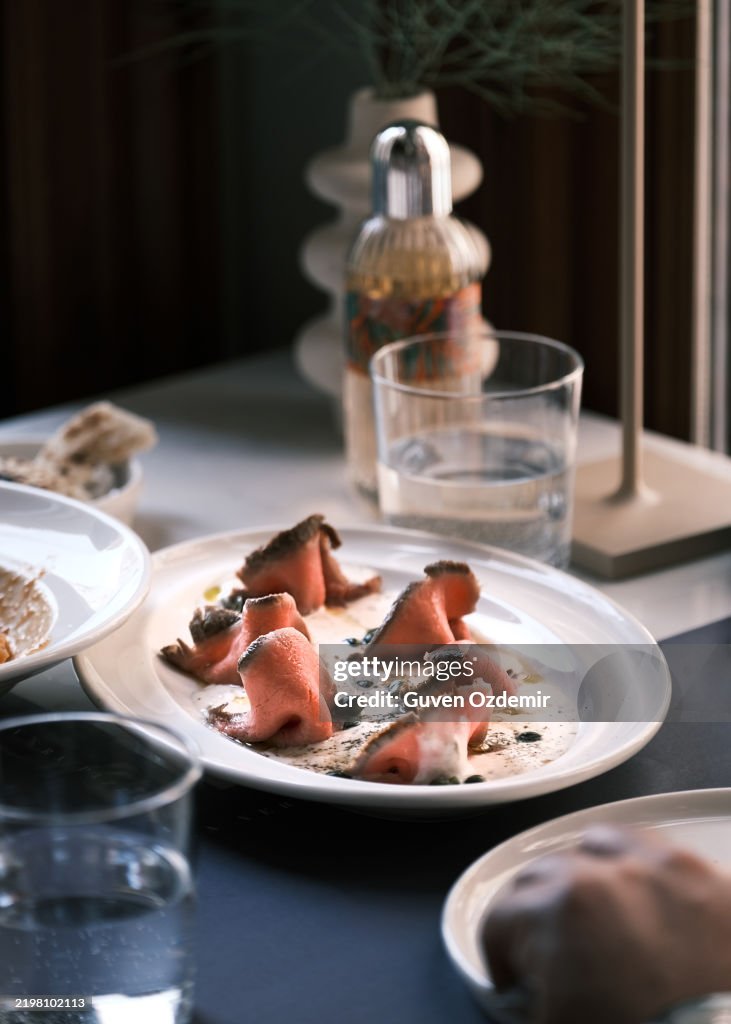 Nahaufnahme von Vitello Tonnato, klassisches italienisches Gericht mit dünn geschnittenem Kalbfleisch und cremiger Thunfischsauce, elegant angerichtet in einem italienischen Restaurant, Fine-Dining- und Gourmet-Cuisine-Konzept