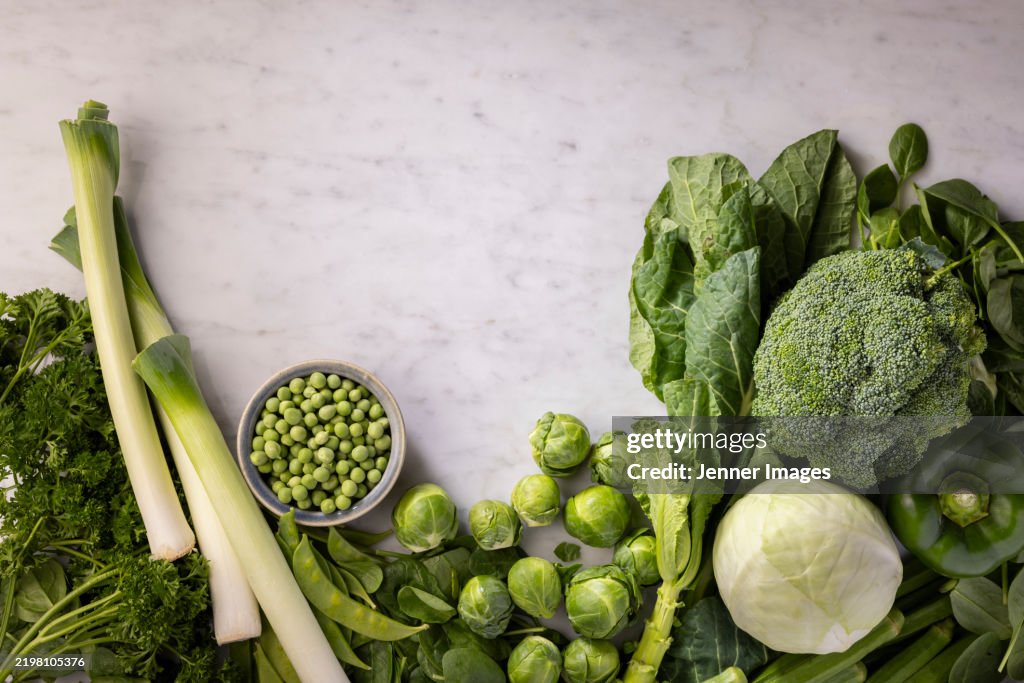 Abundance of fresh green vegetables on a marble background.