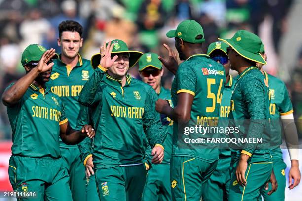 South Africa's Mihlali Mpongwana and Eathan Bosch celebrate with teammates after taking the wicket of New Zealand's Will Young during the Tri-Nation...