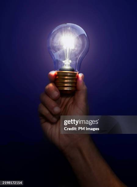 hand holding light bulb - person turning on lamp stock pictures, royalty-free photos & images