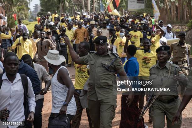 Ugandan police officers escort members of the Patriotic League of Uganda while attempting to march to parliament during a planned anti-corruption...