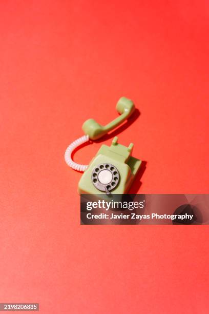 green vintage dial telephone on red background - responder fotografías e imágenes de stock