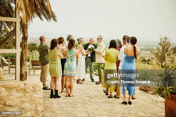 wide shot senior couple exchanging rings at destination wedding - wedding guest stock pictures, royalty-free photos & images