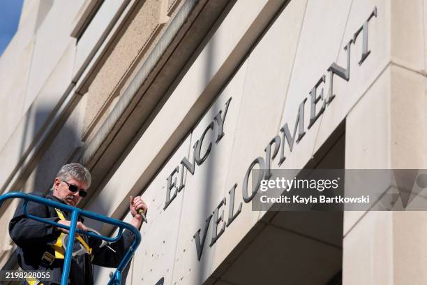 Worker removes the U.S. Agency for International Development sign on their headquarters on February 07, 2025 in Washington, DC. President Donald...