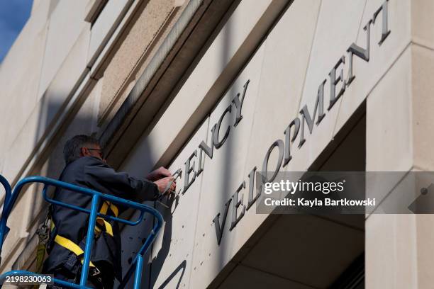 Worker removes the U.S. Agency for International Development sign on their headquarters on February 07, 2025 in Washington, DC. President Donald...