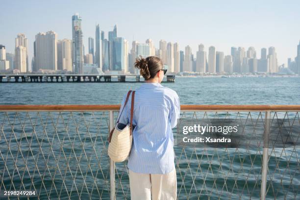 woman looking at the dubai waterfront cityscape - city break stock pictures, royalty-free photos & images