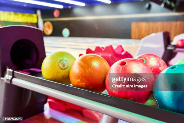 colorful bowling balls resting on a rack, ready for a fun game - bowlingbahn stock-fotos und bilder