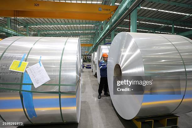 An employee checks a roll of aluminium sheet in a factory which processes aluminium for export in Huaibei, in China's eastern Anhui province on...
