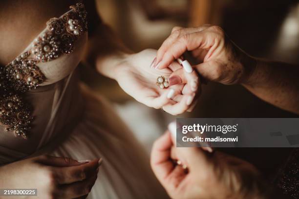 mother helping daughter bride on her wedding day getting dressed - woman putting on diamond stock pictures, royalty-free photos & images