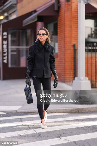 Guest wears black sunglasses, gold earrings, black blazer jacket with black faux fur large collar, shiny black leather gloves, black leather bag,...