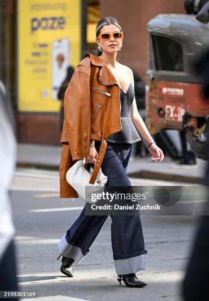Selma Hrapovic is seen wearing a tan leather jacket, black bustier, blue jeans and black heels with white bag outside the Calvin Klein show during...