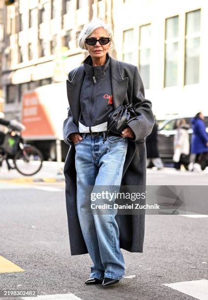 Grece Ghanem is seen wearing a gray coat, gray zippered jacket, blue jeans and black sunglasses outside the Calvin Klein show during NYFW F/W 2025 on...