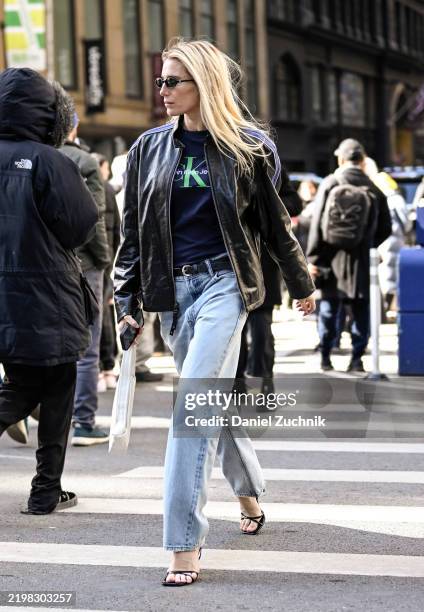 Guest is seen wearing a black leather jacket, Calvin Klein top, blue jeans and black heels with black sunglasses outside the Calvin Klein show during...