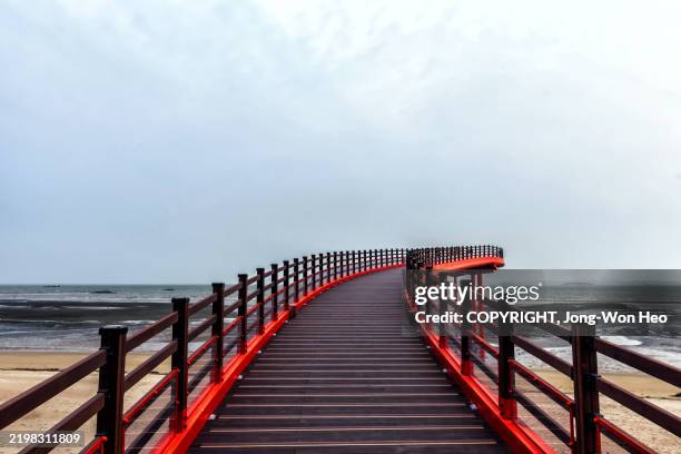modern coastal wooden walkway with red railings over calm sea - chungcheongnam do province stock pictures, royalty-free photos & images