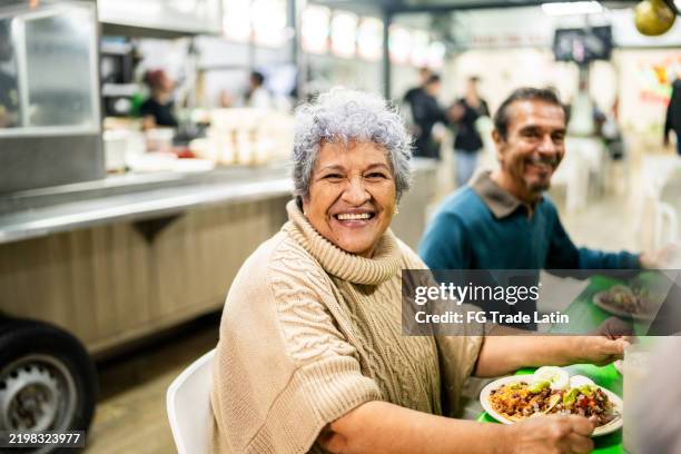 porträt einer älteren frau, die mexikanisches essen mit freunden in einem restaurant isst - tortilla stock-fotos und bilder